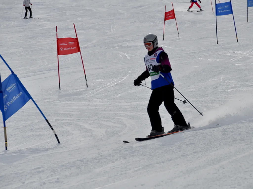 Skifahrer mit Helm zieht eine Kurve neben dem blauen Tor.